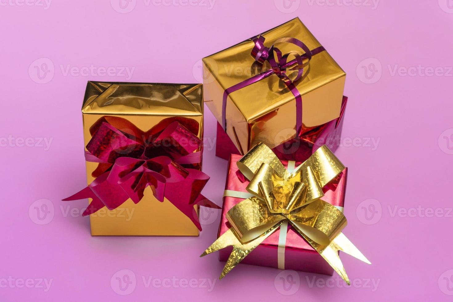 Beautiful golden gift boxes with a red bow on a colored background, top view photo