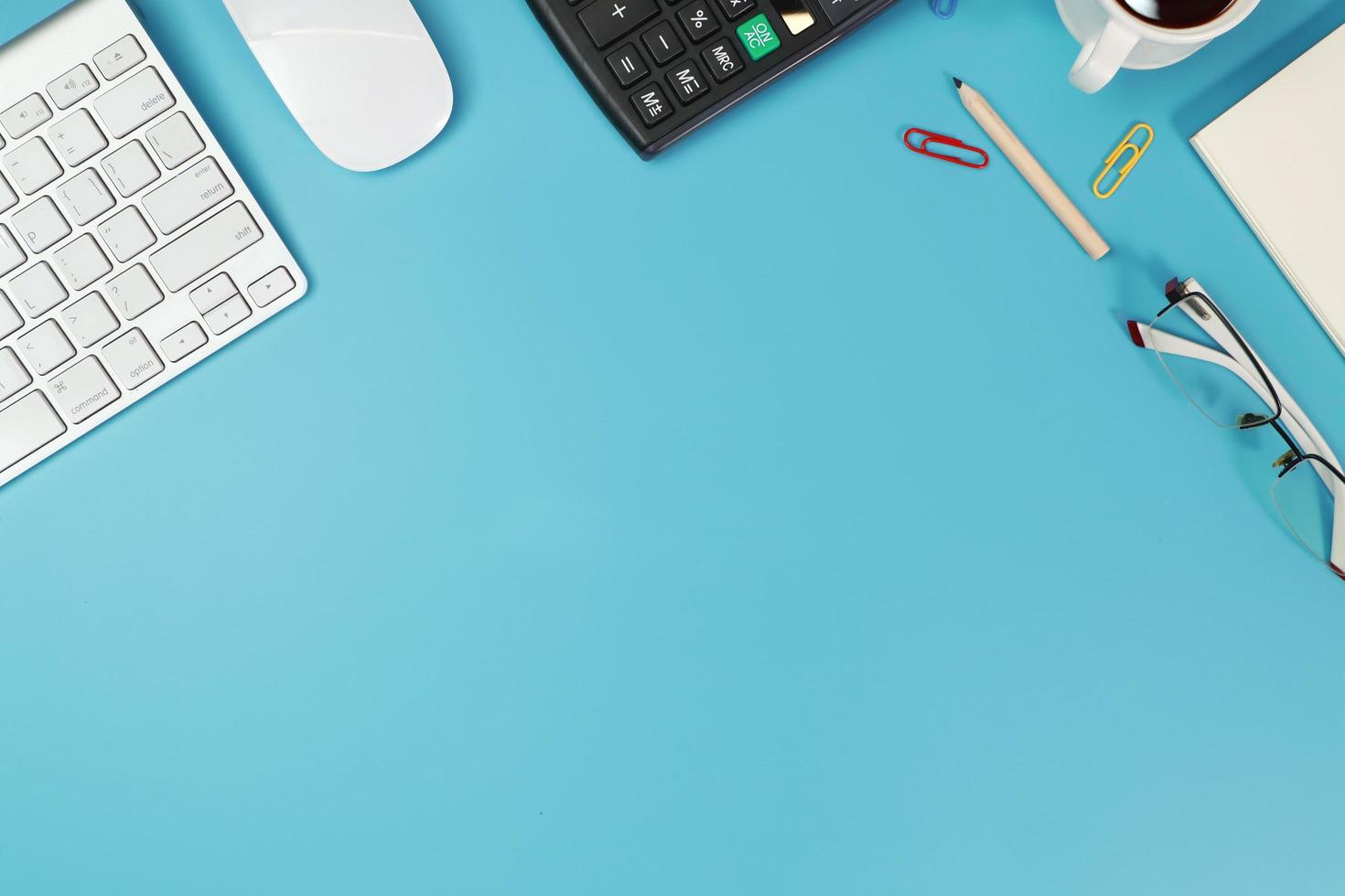 workspace business desk with computer, glasses, calculator, banknote and pencil on blue background photo