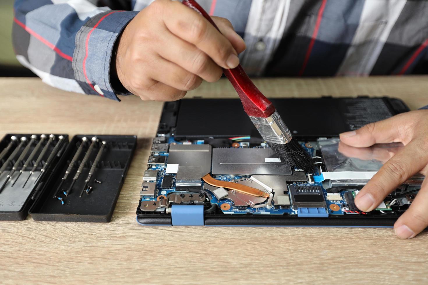 technician man using a dusting brush to clean laptop computer photo