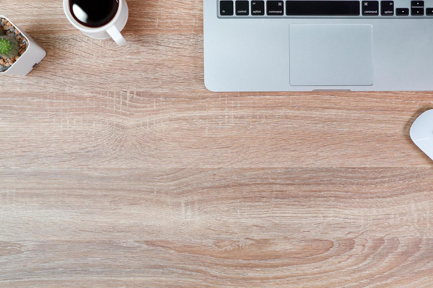 mesa de madera de trabajo de tecnología con computadora portátil, taza de café y planta foto