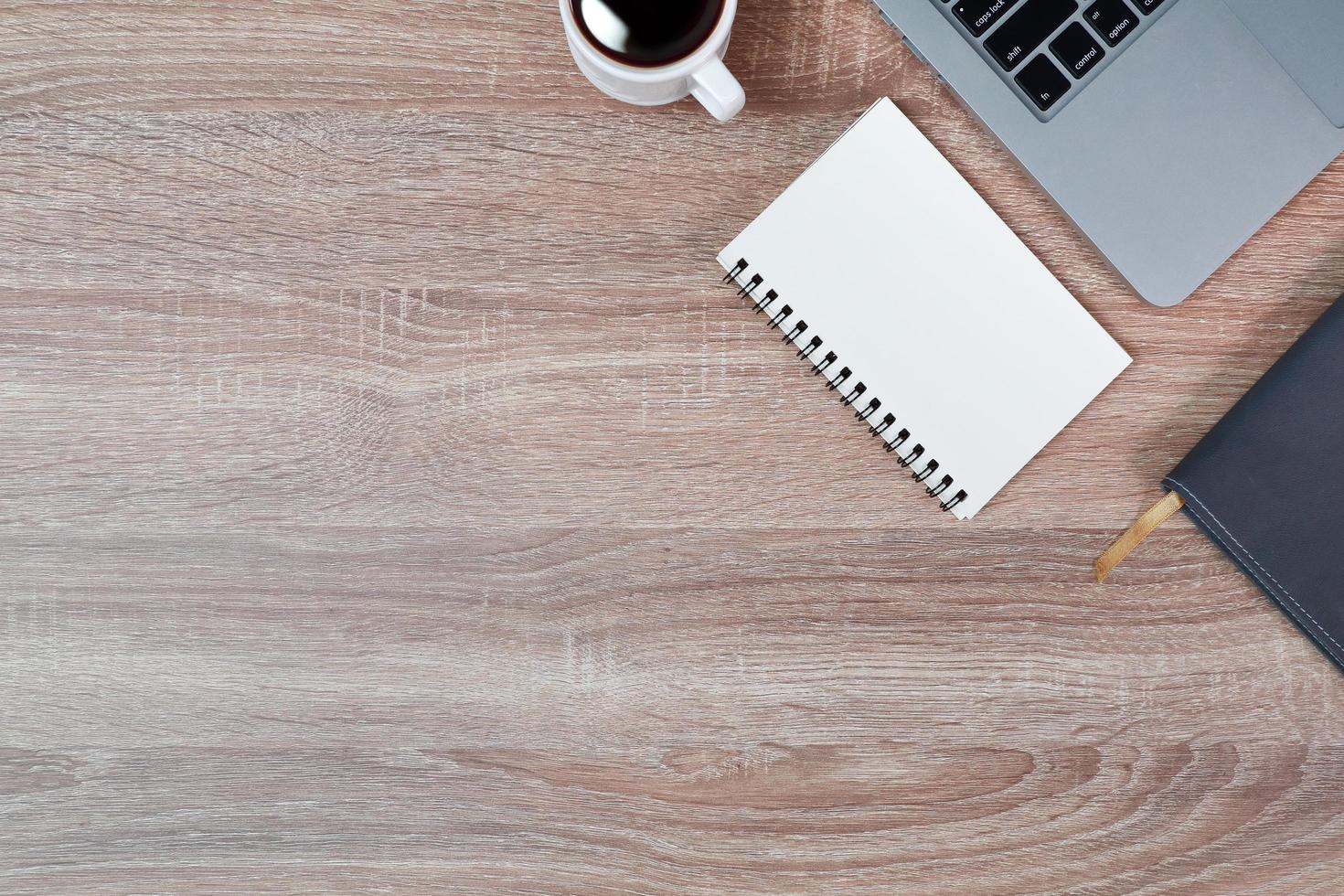 mesa de madera de trabajo de tecnología con computadora portátil, taza de café y planta foto