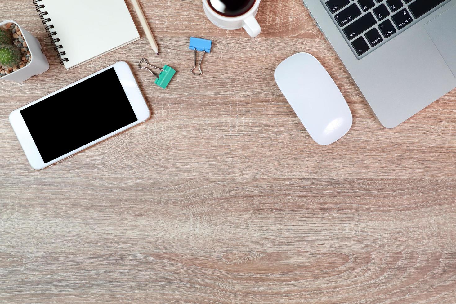 mesa de madera de trabajo de tecnología con computadora portátil, taza de café y planta foto