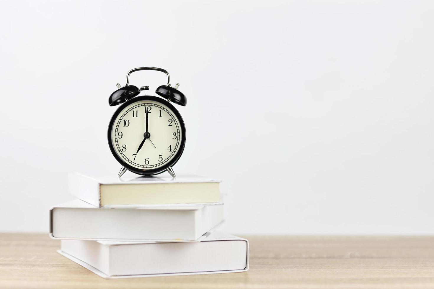 alarm clock with books on wooden desk and white background photo