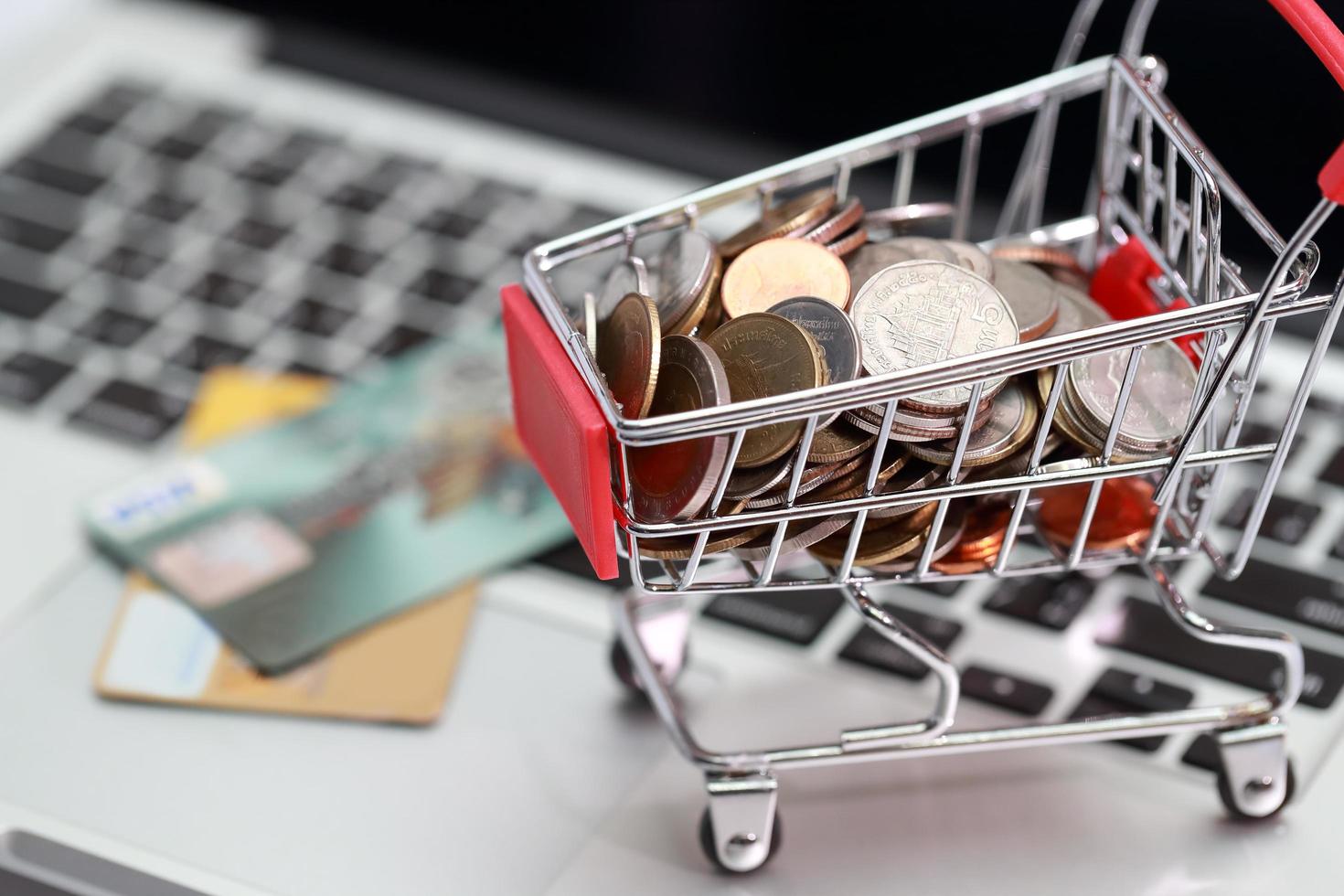trolley with coins and credit cards on computer, idea for shopping and online payment using as business background photo