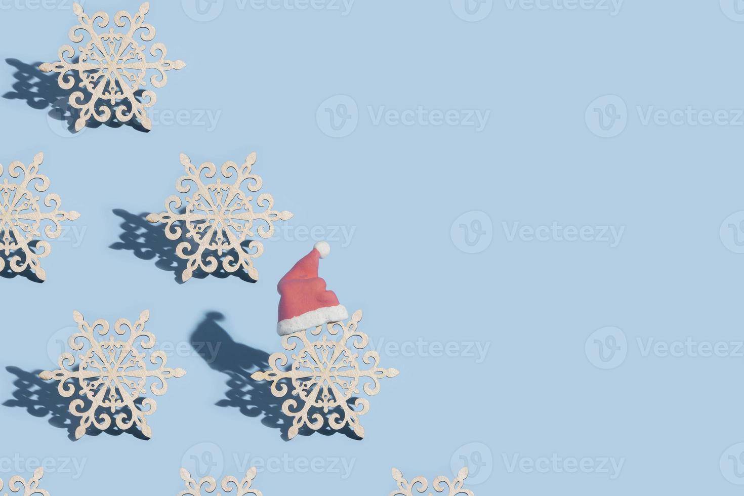 A pattern of snowflakes, one of which is wearing a Santa hat, on a blue background photo