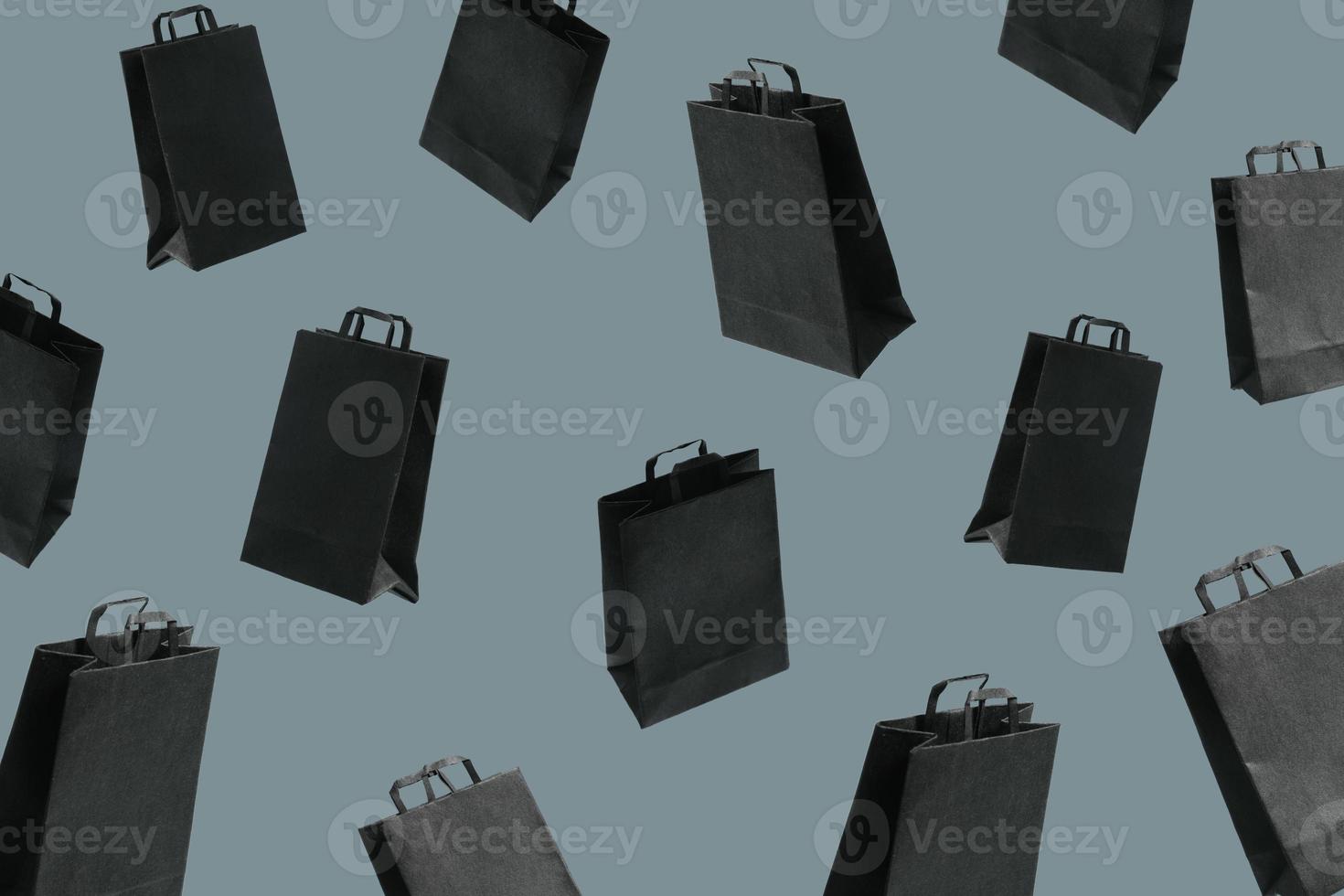 Pattern from black sale shopping bags are flying on yellow background. Black Friday creative concept photo
