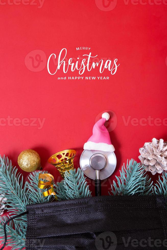 Merry Christmas text with medical stethoscope in santa hat and christmas decorations on red background photo