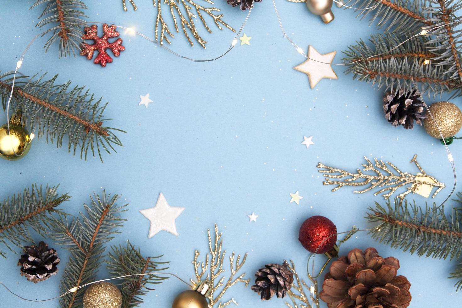 Christmas flat lay. Concept photo Christmas and New Year holiday. Fir tree and golden twigs, cones, stars, garlands and snowflake on a blue background. Copy space for text