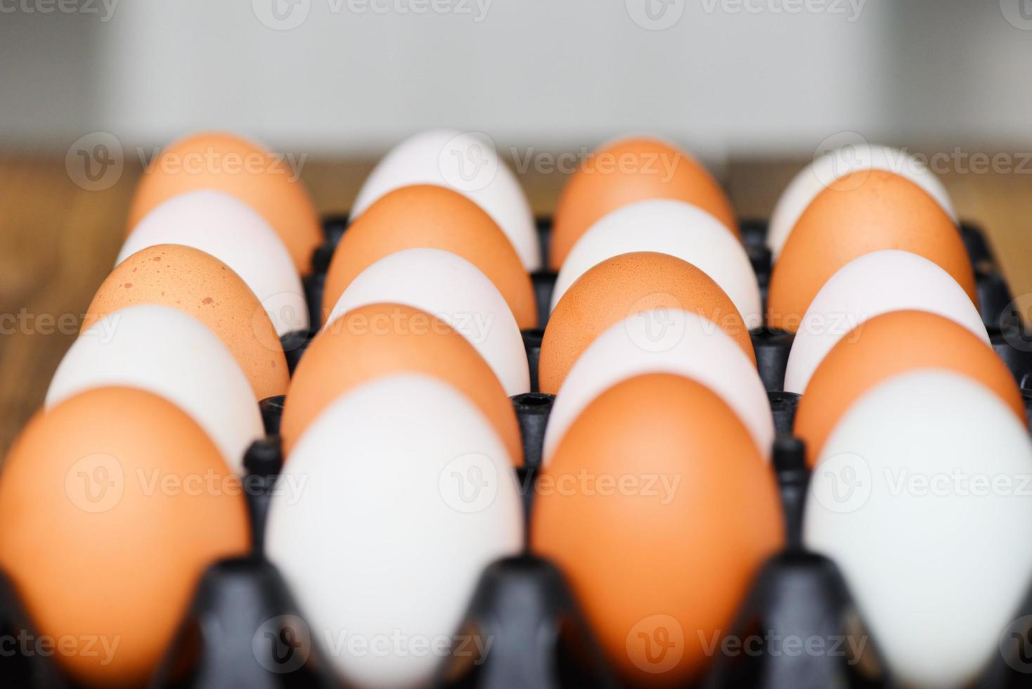 Huevos de gallina frescos y huevos de pato en caja sobre fondo de mesa de madera. foto