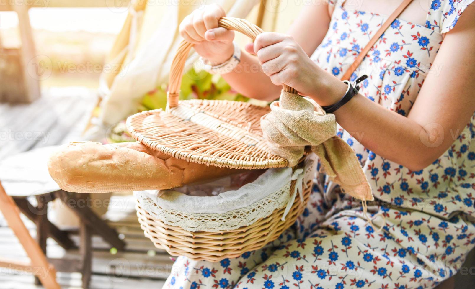 Mujer sosteniendo bollos horneados de delicioso pan fragante en el canasto foto