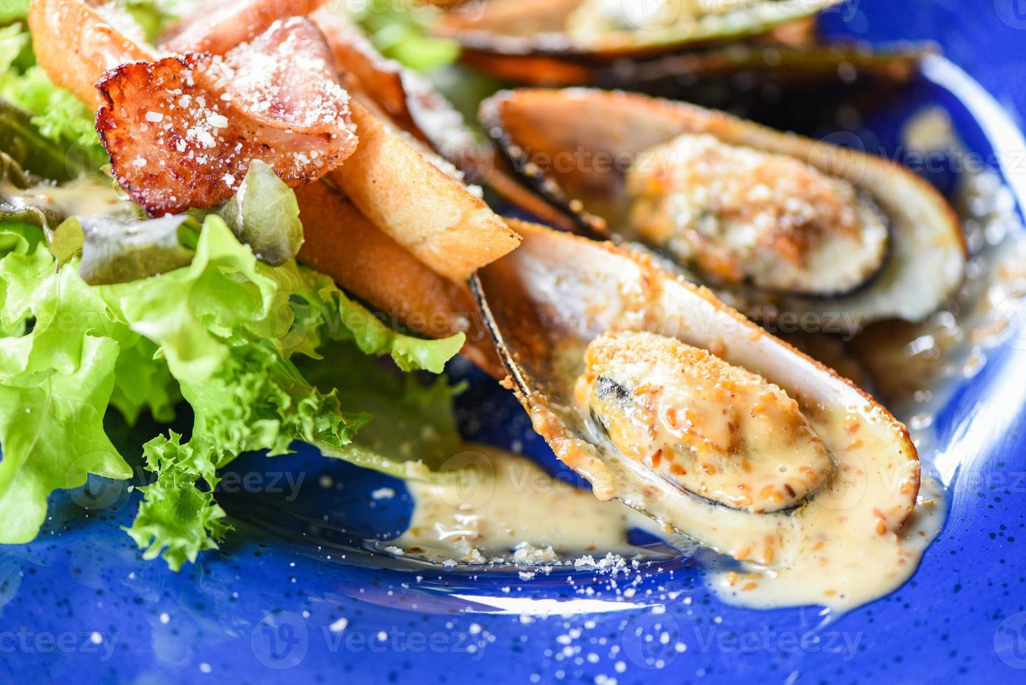 Shellfish seafood plate fresh mussel baked with cheese dinner food cooked - Grilled mussel shell ham vegetables and sauce seafood served on table photo