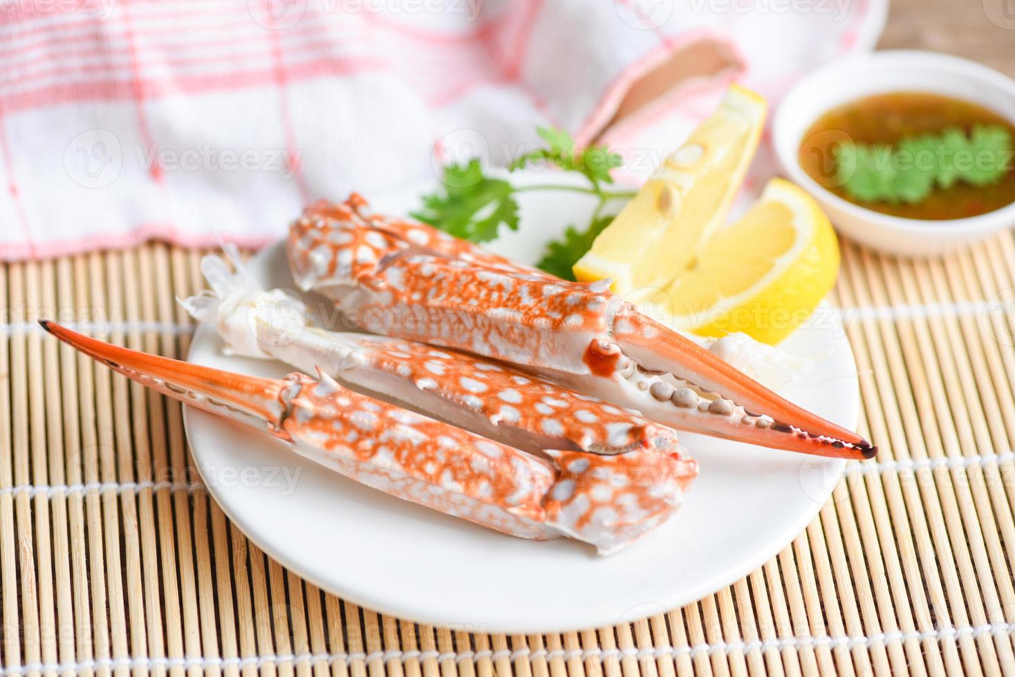 Comida de cangrejo hervida en un plato blanco y salsa de mariscos en la mesa - mariscos pinzas de cangrejo foto