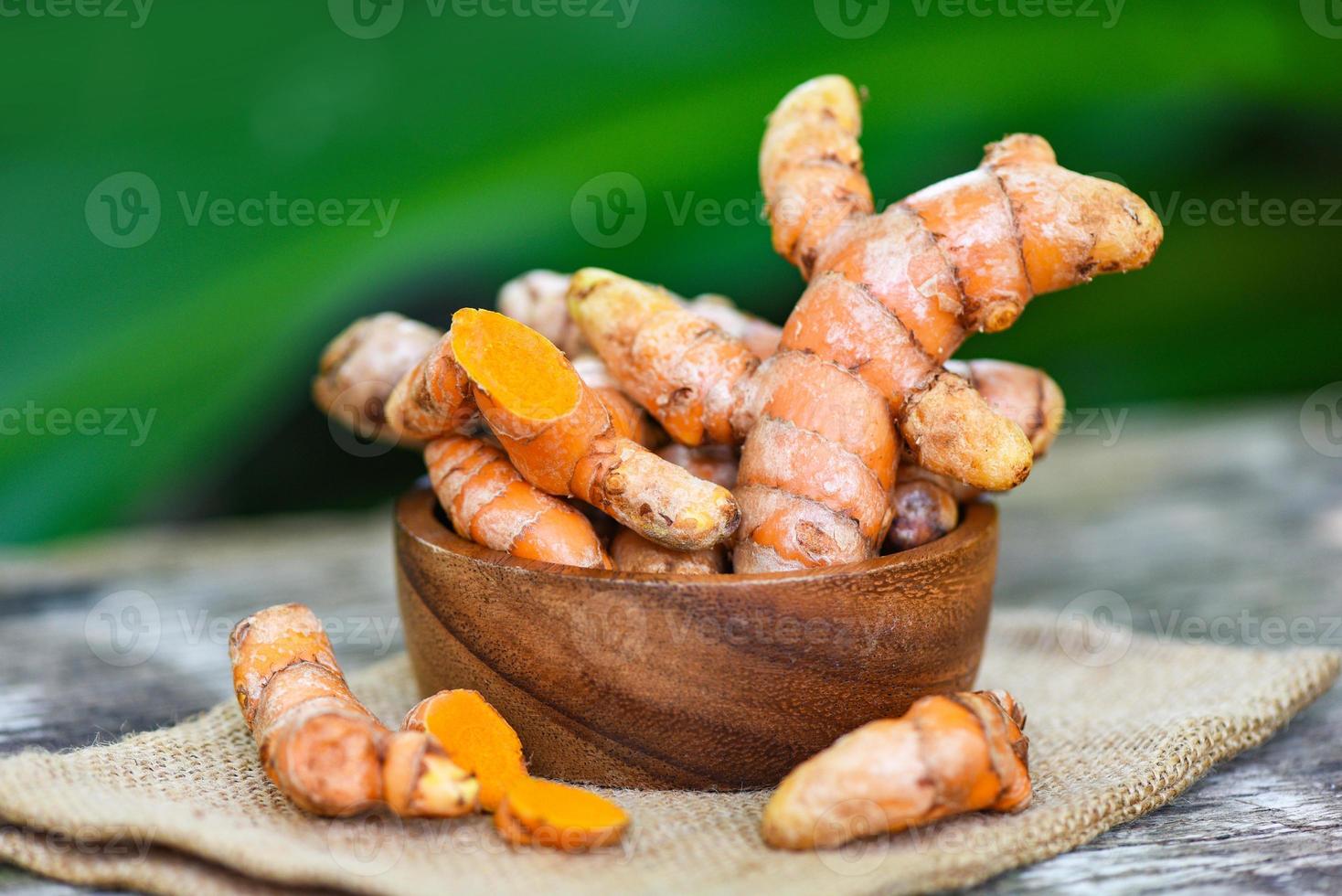 turmeric on wooden bowl , fresh turmeric root and for nature medicine herb and cooked ingredient food. photo