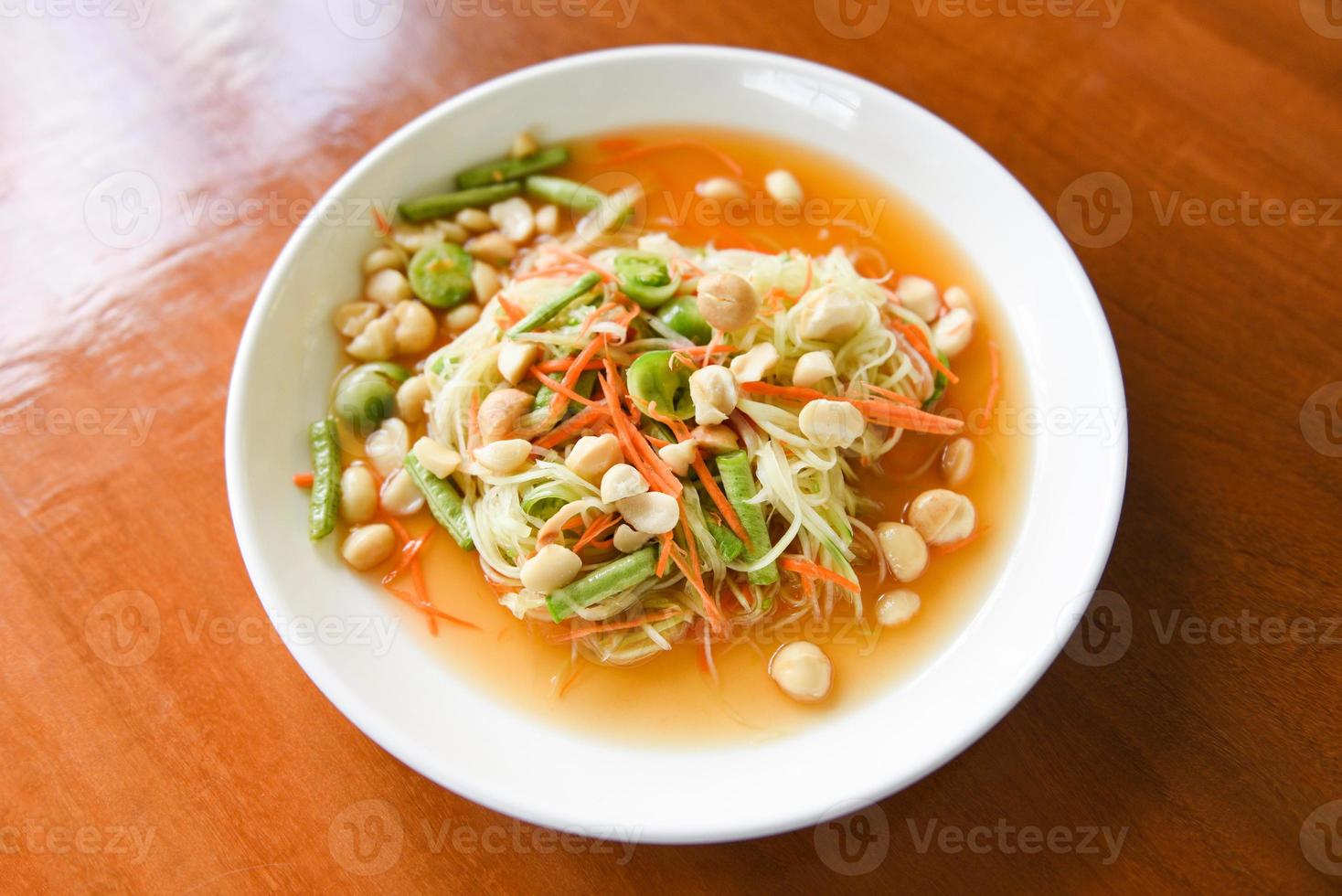 Ensalada de papaya de comida tailandesa con nueces de macadamia en la parte superior de la placa blanca comida sana foto