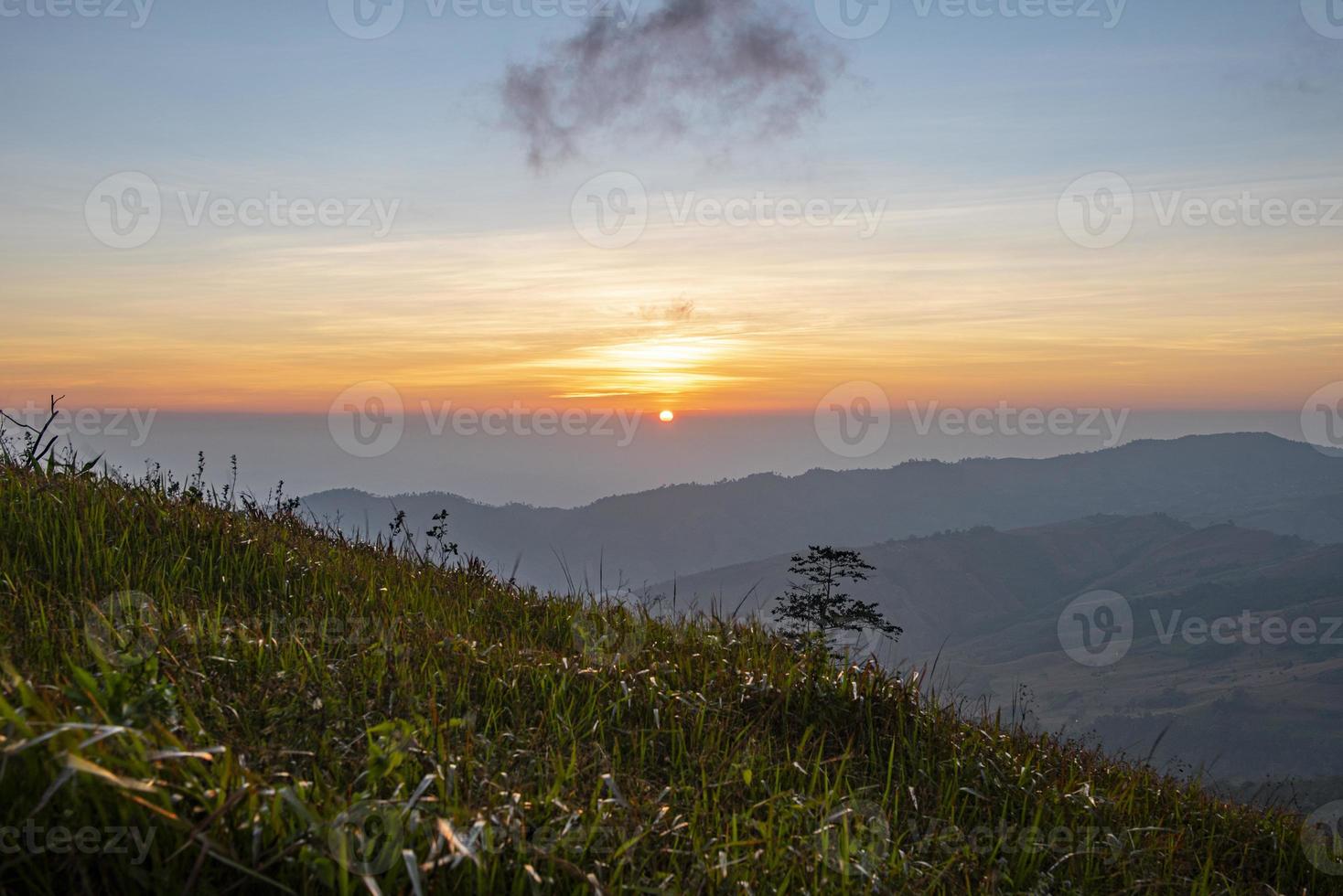 Landscape sunrise on the mountain with field and grass meadow beautiful sky. photo