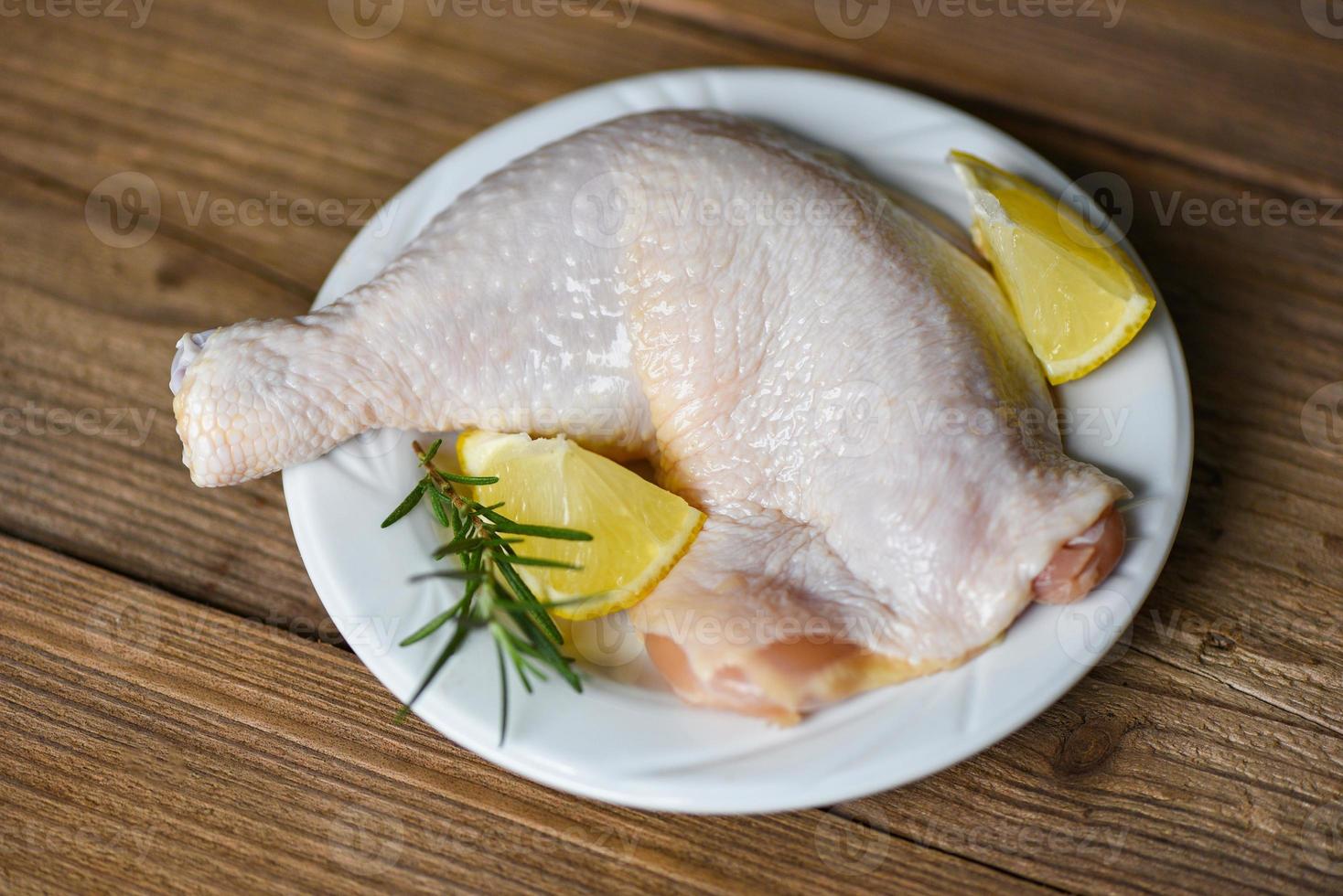 Raw chicken leg on white plate for cooking thai asian food rosemary chicken lemon on wooden food table photo