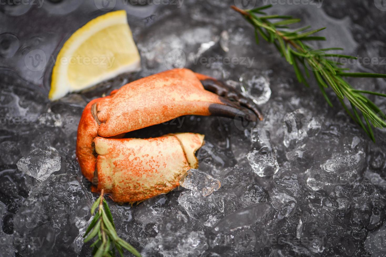 Seafood frozen boiled crab claws Fresh crab with ingredients lemon rosemary on ice at market photo