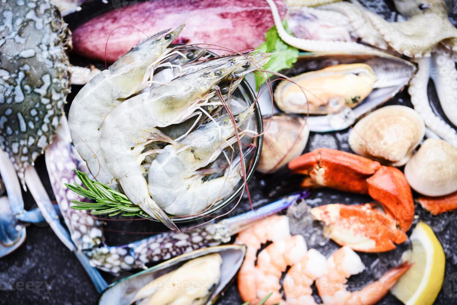 Seafood shellfish on ice frozen with shrimps prawns crab claws shell clam squids octopus and mussels at the restaurant Fresh raw seafood buffet with lemon rosemary ingredients herb and spices photo