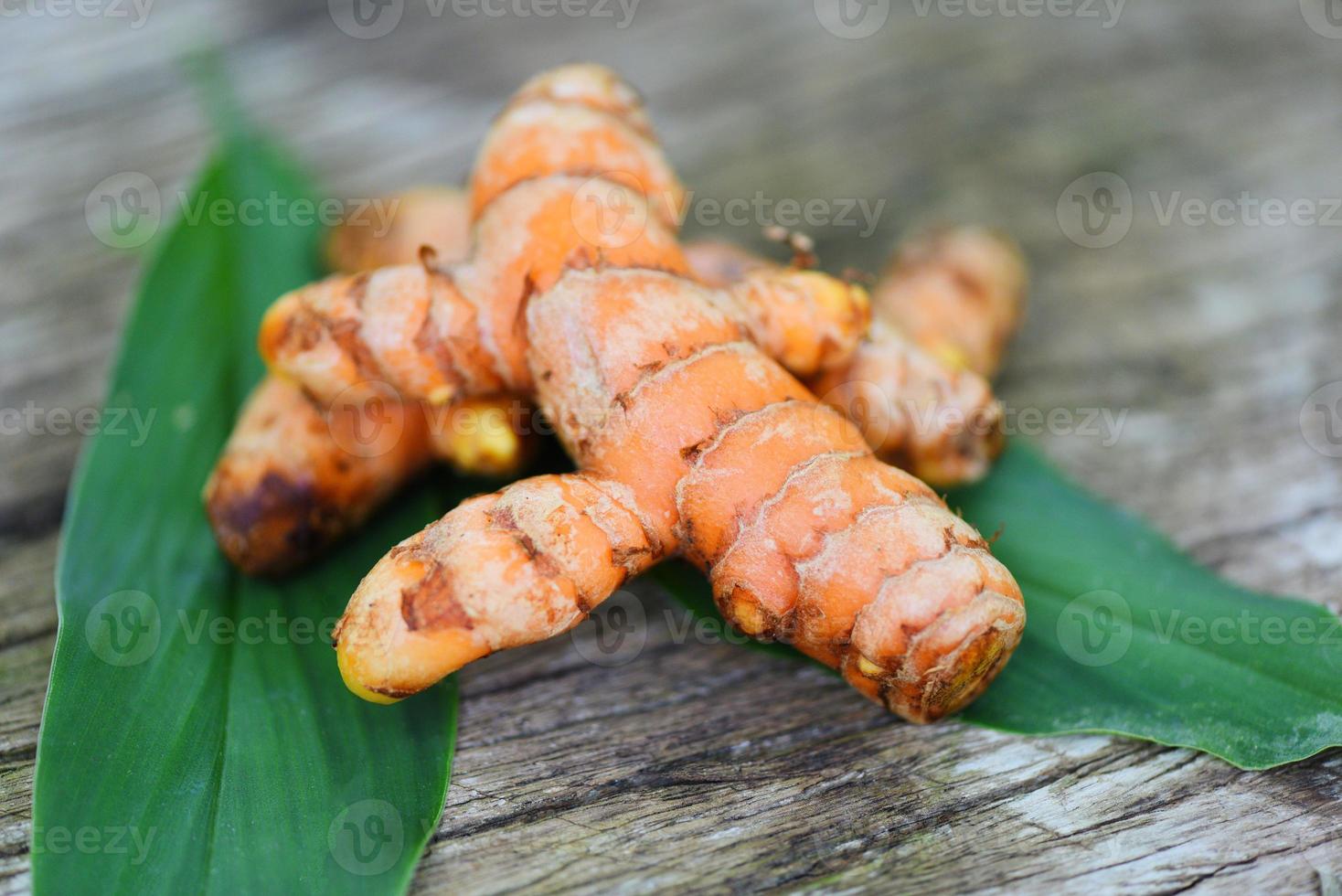 cúrcuma en madera, raíz de cúrcuma fresca y hojas verdes para hierbas medicinales naturales y alimentos de ingredientes cocidos. foto