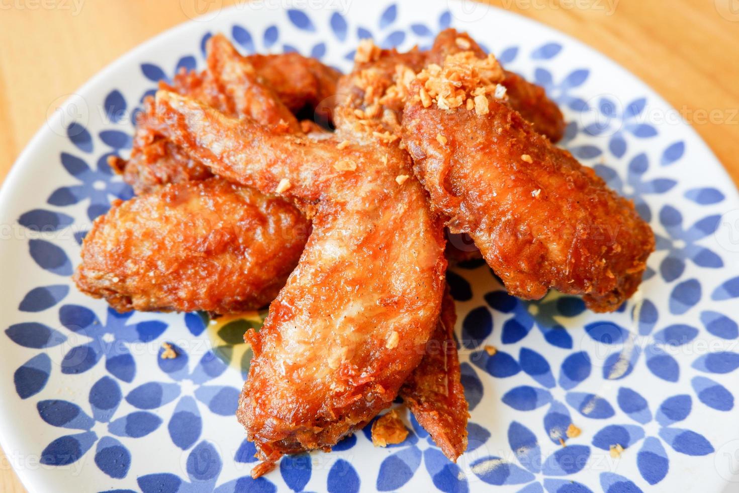 Fried chicken wings with garlic on plate and wooden table food. photo