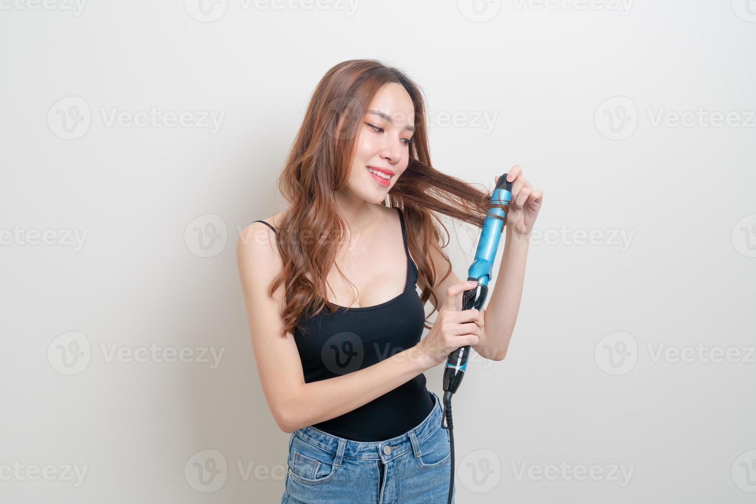 Retrato hermosa mujer asiática con rizador de pelo o rizador foto