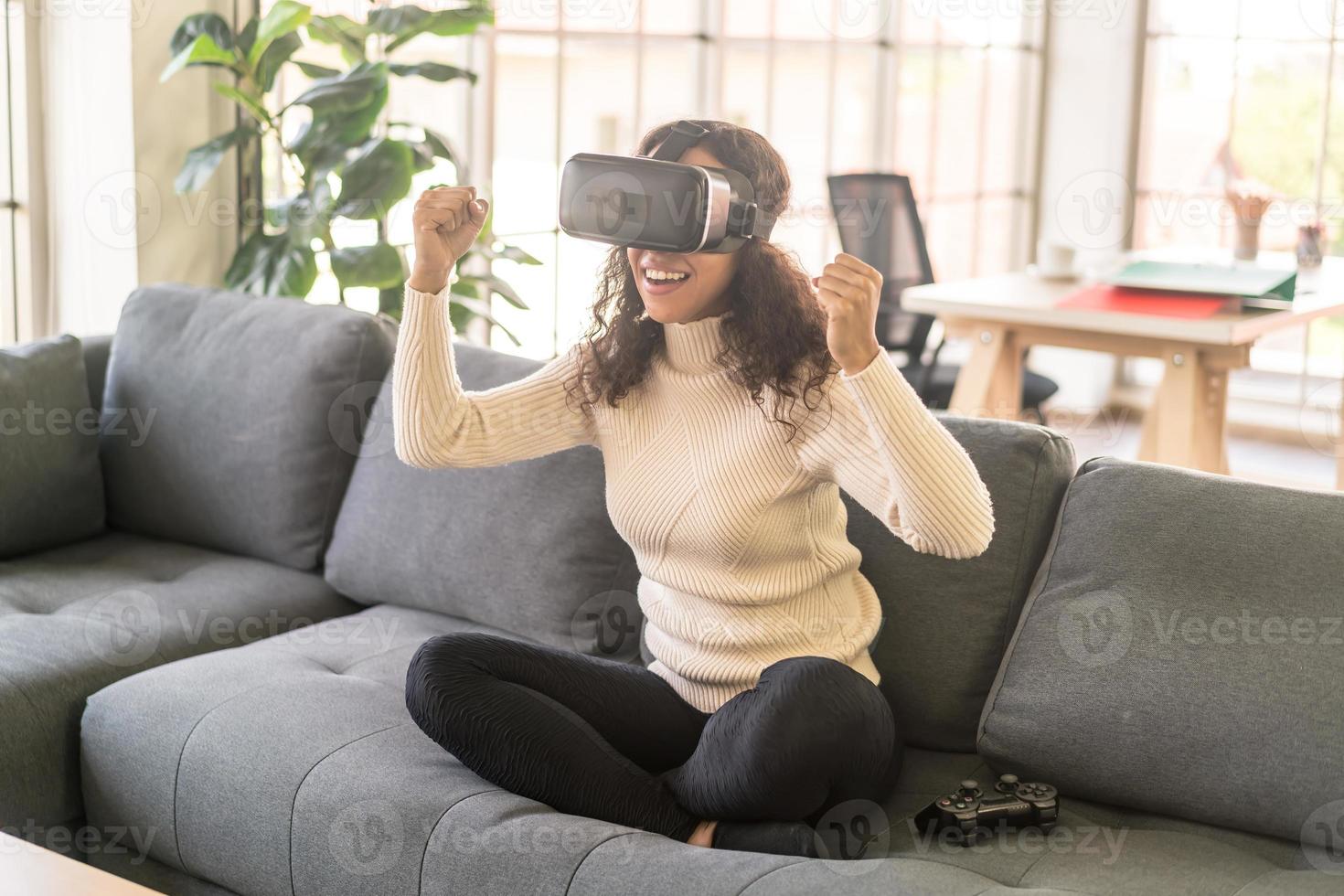 Mujer latina con un casco de realidad virtual en el sofá foto