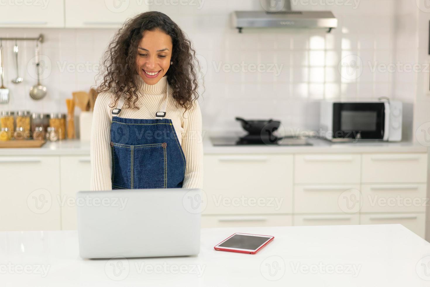 Mujer latina buscando receta para cocinar en la cocina foto