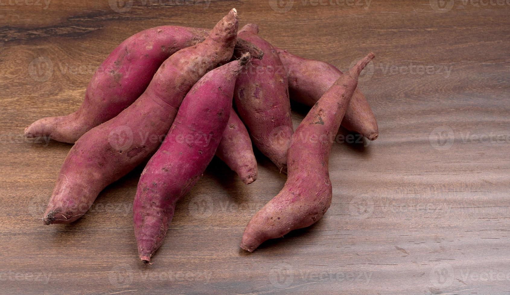 slices of sweet potatoes on wooden background, close up. Raw sweet potatoes or batatas. photo