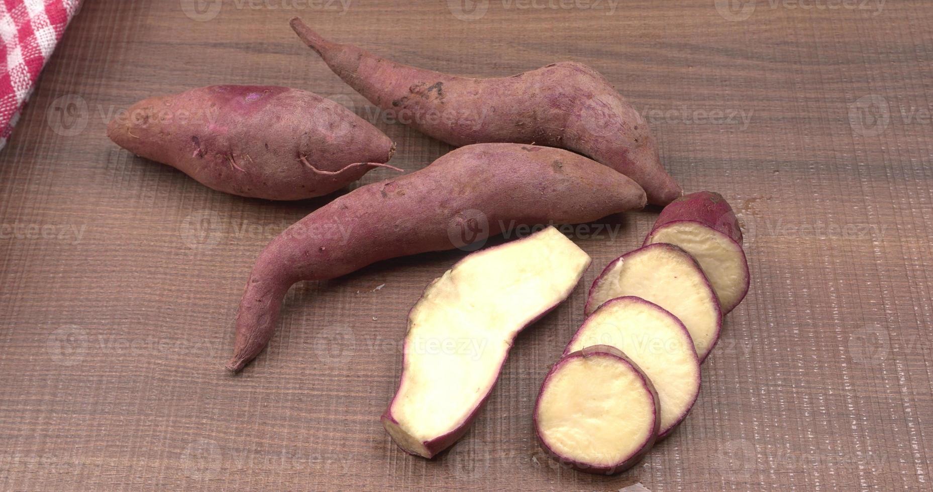 slices of sweet potatoes on wooden background, close up. Raw sweet potatoes or batatas. photo