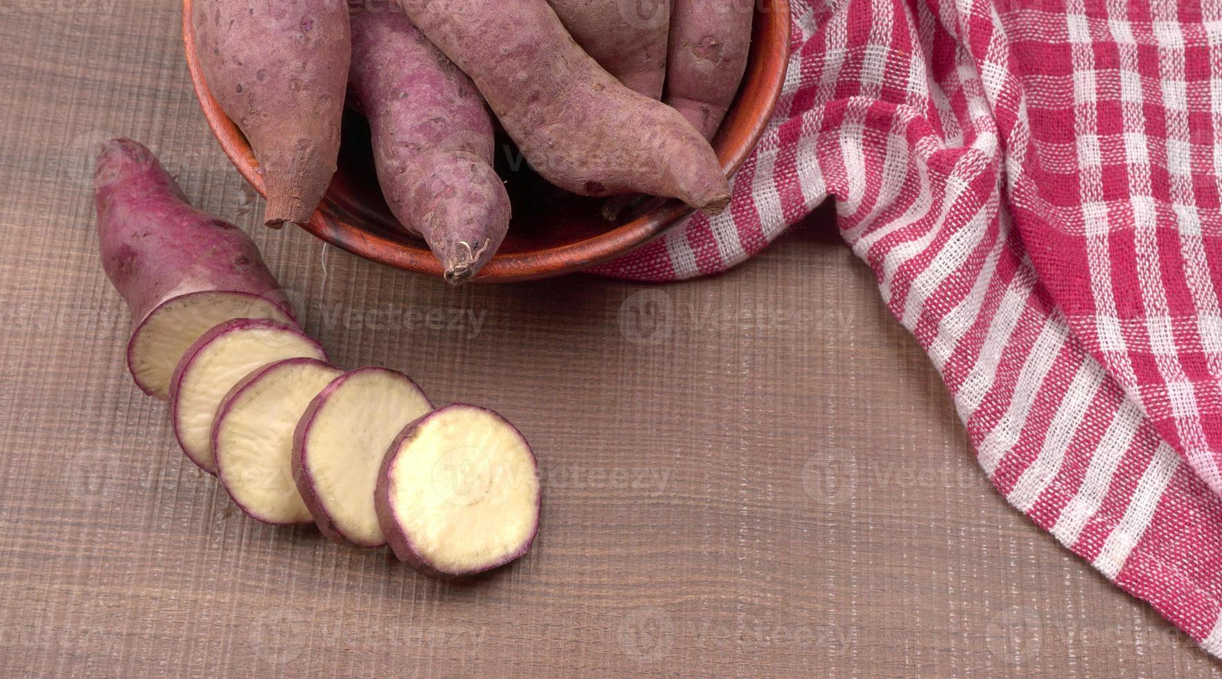slices of sweet potatoes on wooden background, close up. Raw sweet potatoes or batatas. photo