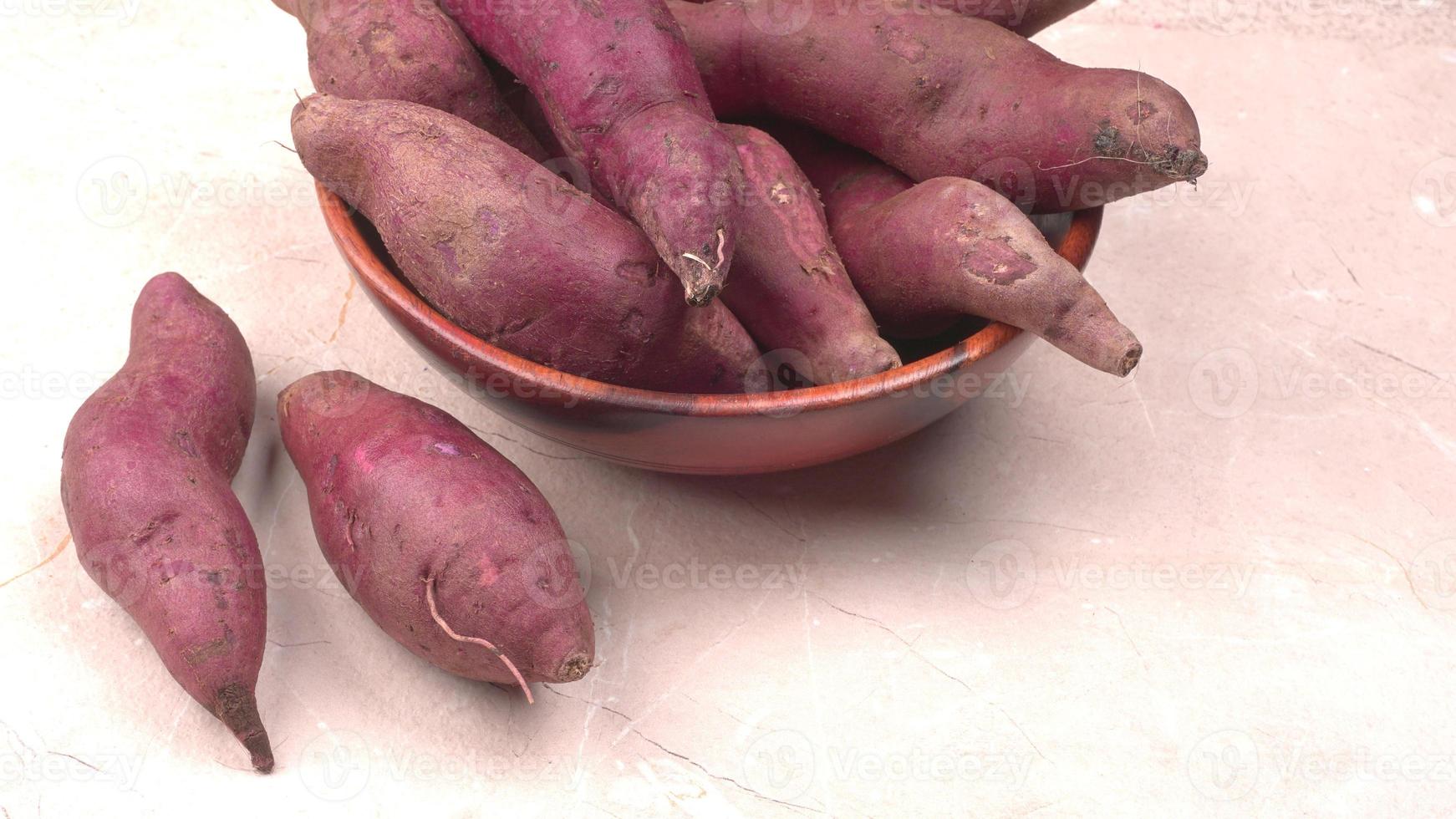 slices of sweet potatoes on wooden background, close up. Raw sweet potatoes or batatas. photo