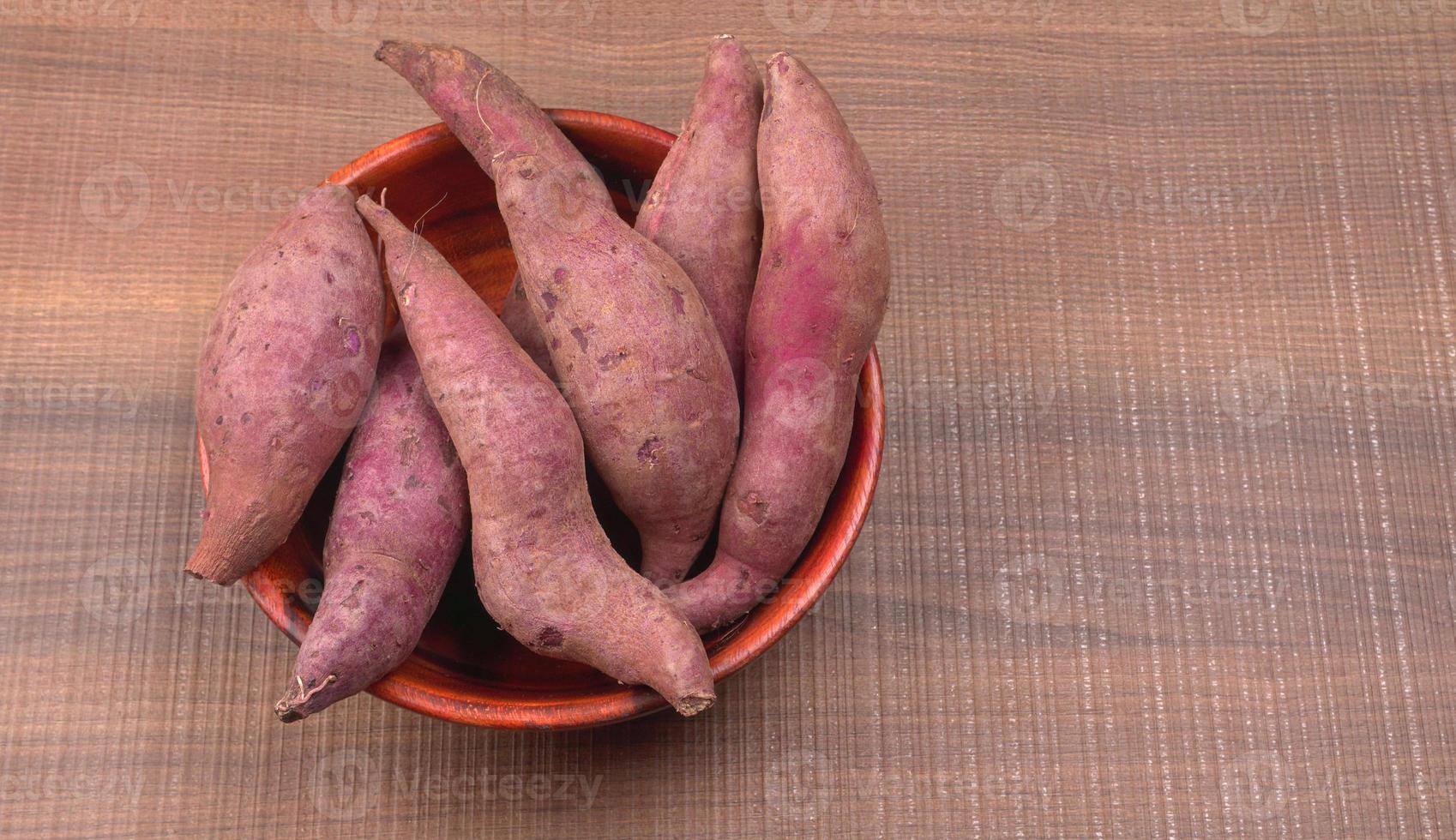 slices of sweet potatoes on wooden background, close up. Raw sweet potatoes or batatas. photo