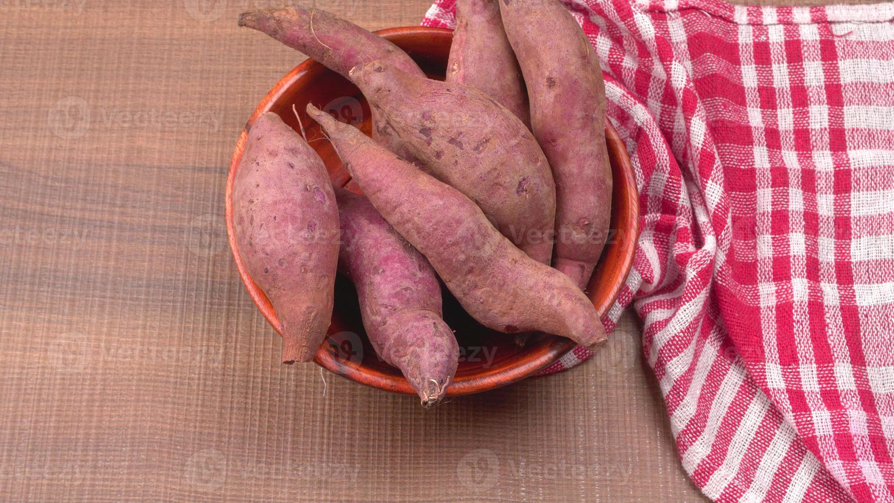 slices of sweet potatoes on wooden background, close up. Raw sweet potatoes or batatas. photo