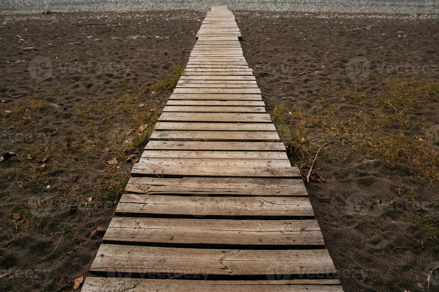 camino de madera en la playa de arena. Paseo marítimo de playa con fondo de textura de arena foto