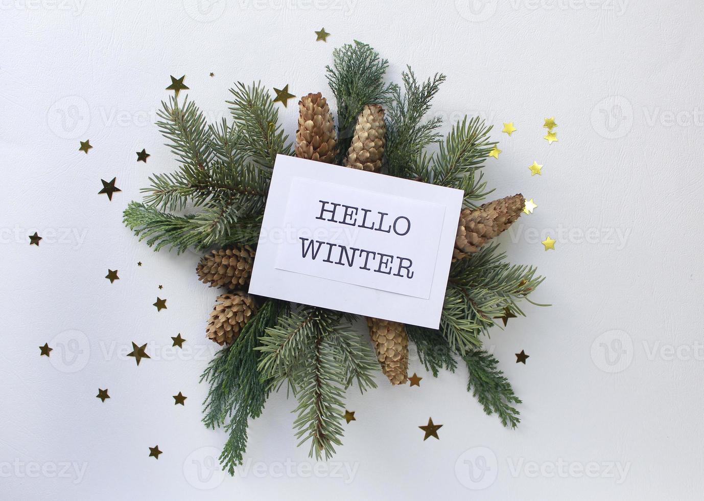Hello winter greeting card, fir tree branches, cones and festive decor on white background, flat lay photo