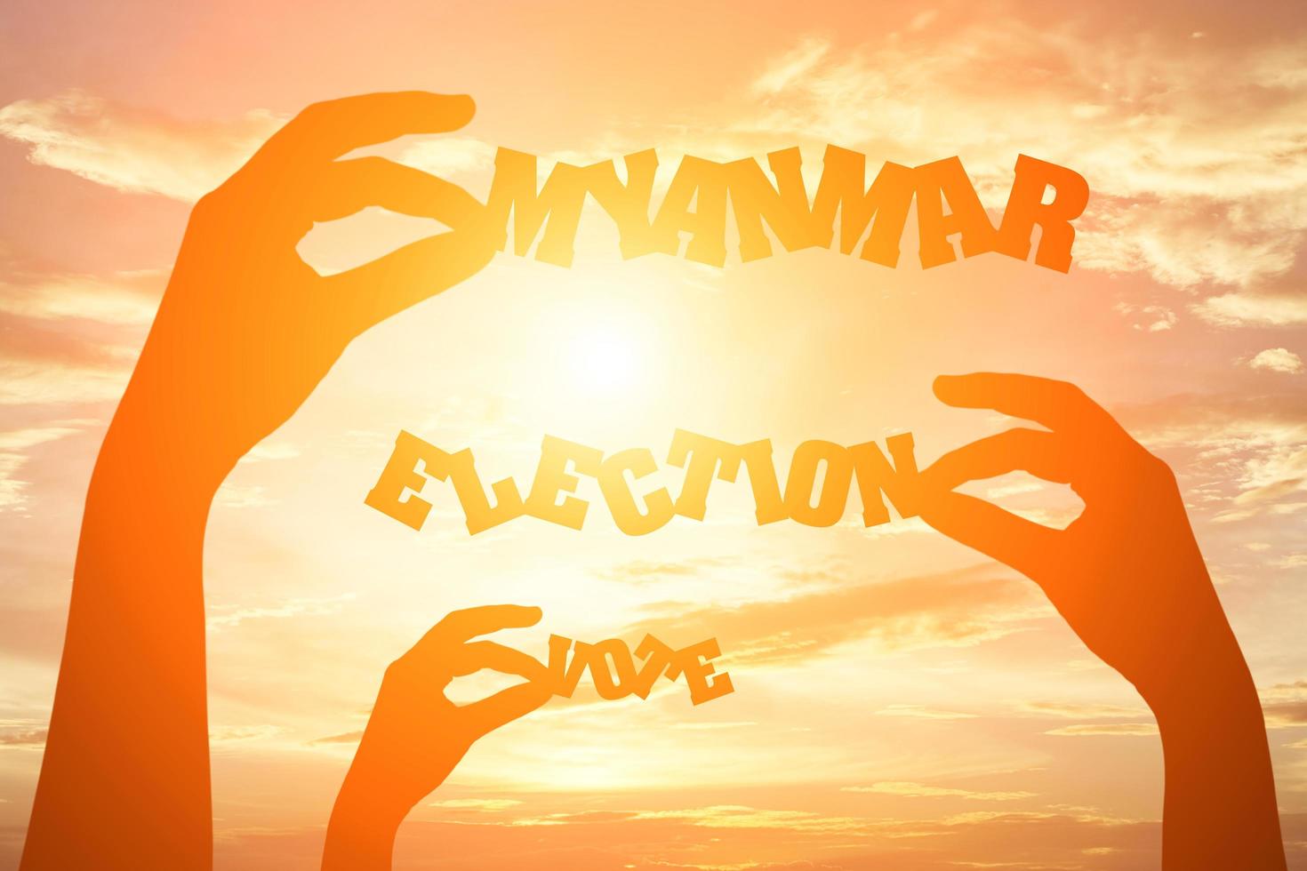 Silhouette of hand holding paper cut text MYANMAR ELECTION VOTE photo