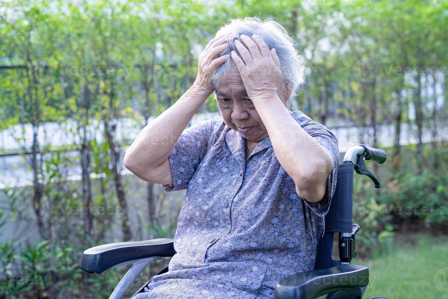 Asia mayor o anciana anciana paciente dolor de cabeza mientras está sentado en la cama en la sala del hospital de enfermería, sano concepto médico foto