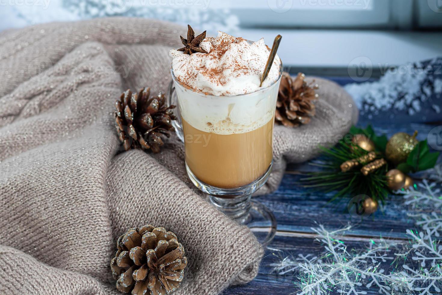 café con leche caliente con ramas de canela, espolvoreado con canela. adornos navideños, ramas de un árbol de navidad. concepto de vacaciones año nuevo. foto