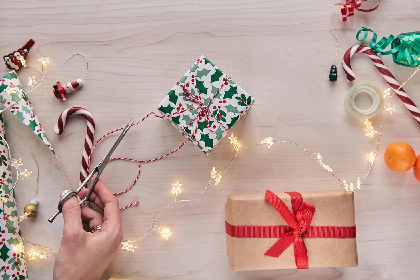 Christmas composition. Giftboxes, presents wrapping with paper and ribbon, lights, candy canes on wooden background. Holdiay DIY handmade home decoration. Winter, new year Flat lay, top view photo