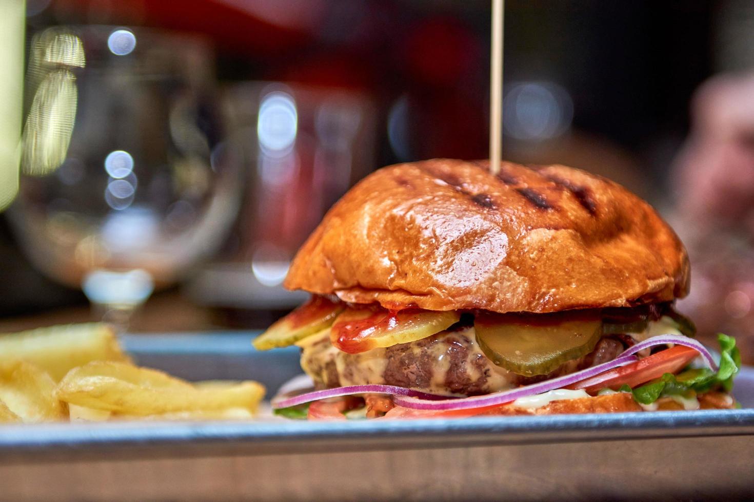 Tasty grilled burger with beef,cheese,bacon and sauce on wooden table with french fries and beer photo