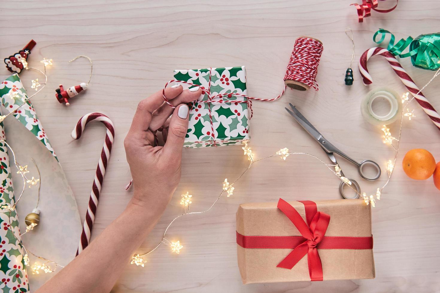 Christmas composition. Giftboxes, presents wrapping with paper and ribbon, lights, candy canes on wooden background. Holdiay DIY handmade home decoration. Winter, new year Flat lay, top view photo