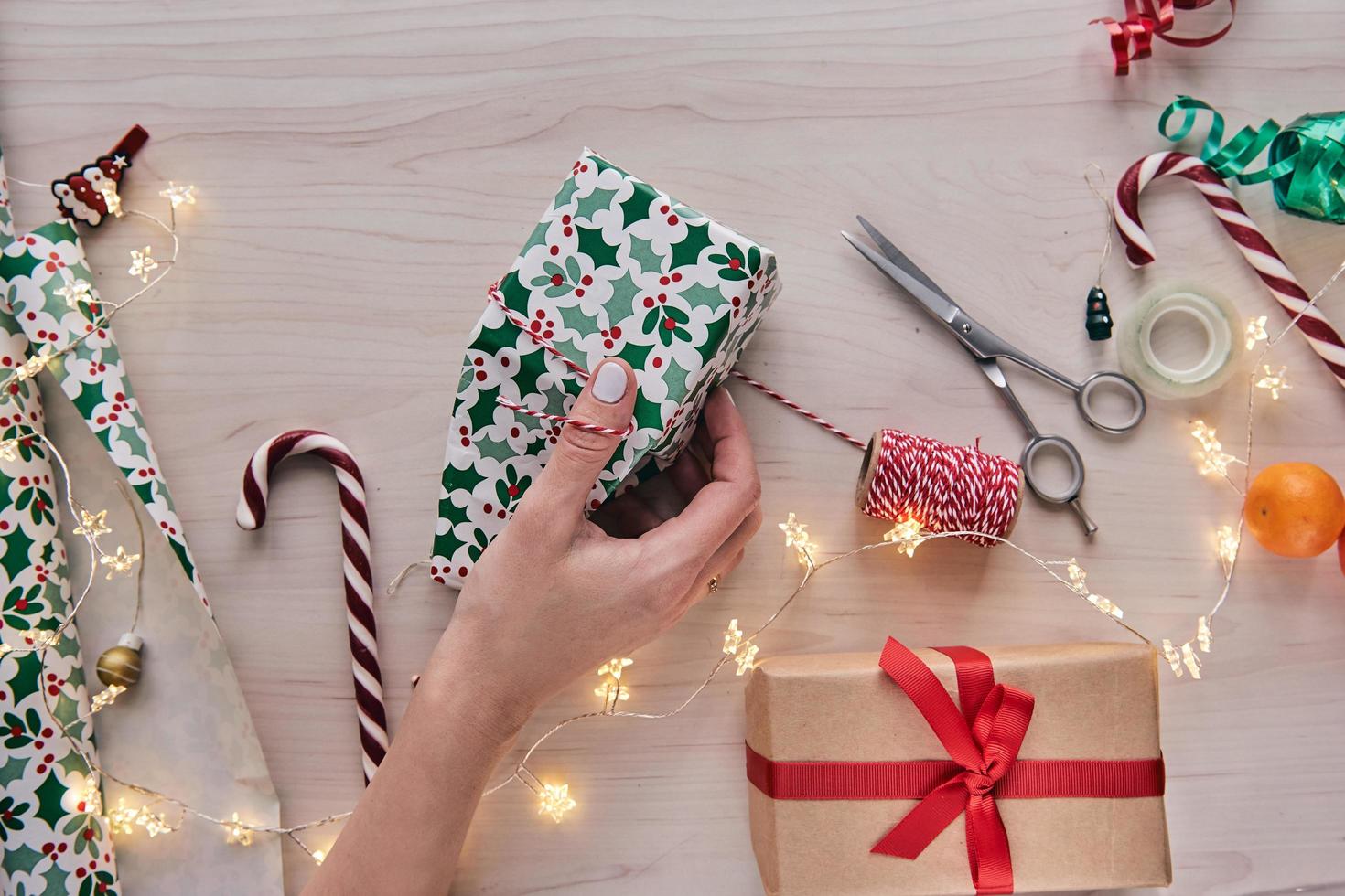 Christmas composition. Giftboxes, presents wrapping with paper and ribbon, lights, candy canes on wooden background. Holdiay DIY handmade home decoration. Winter, new year Flat lay, top view photo