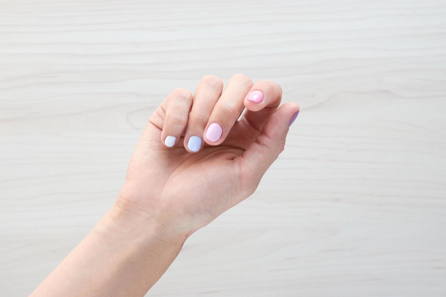 Stylish trendy female pastel white, pink and blue manicure. Beautiful young woman's hands on wooden background. Copy space banner photo