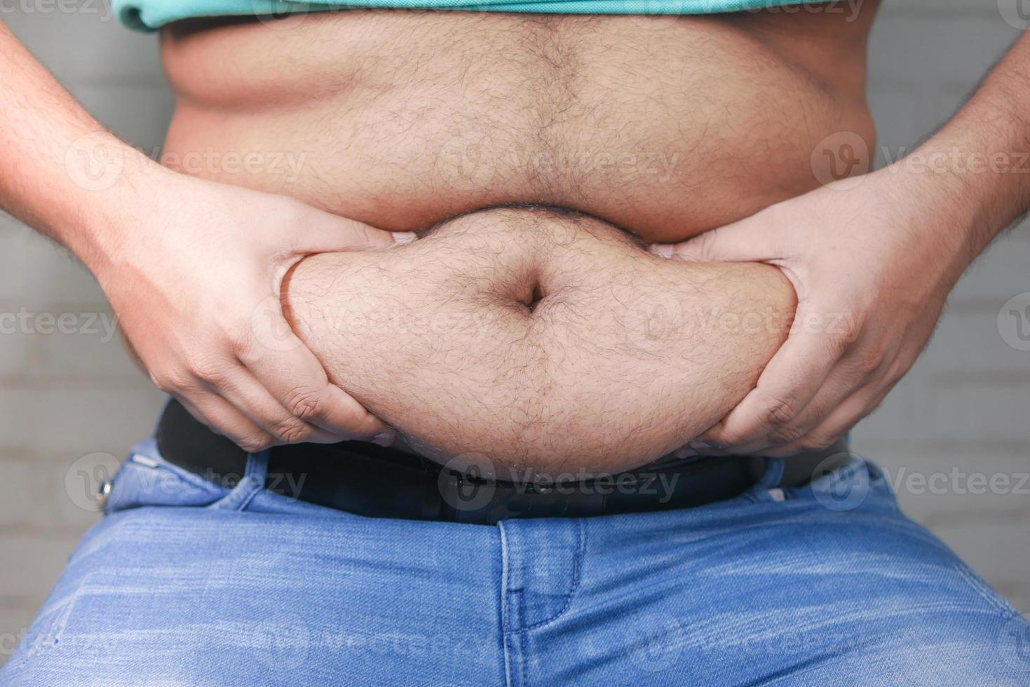 man's hand holding excessive belly fat, overweight concept photo