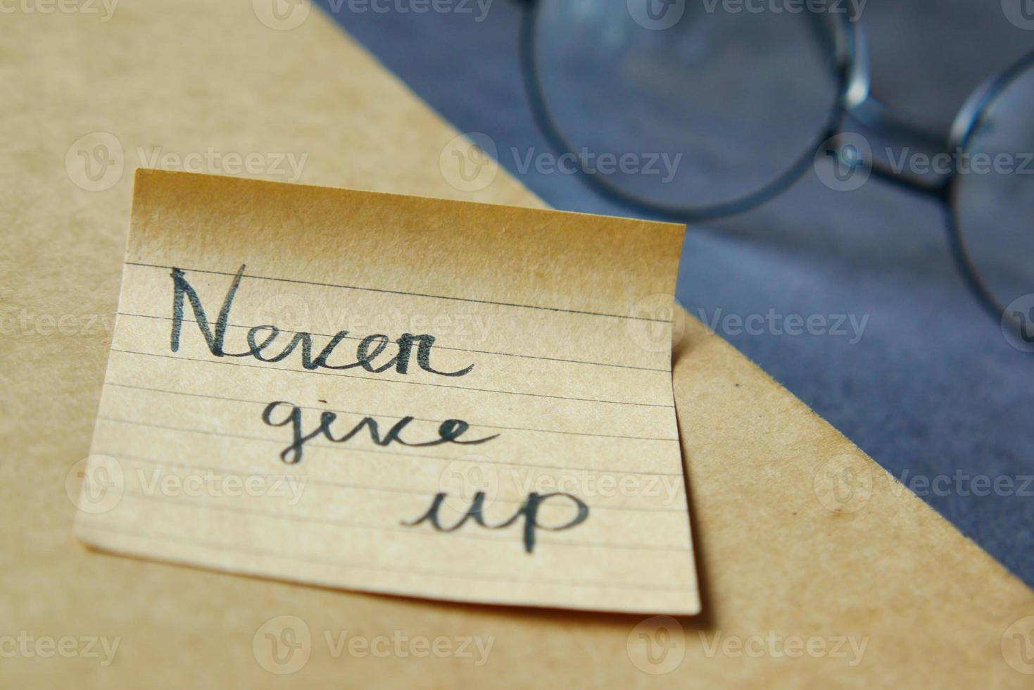 never give up word on stick note on table , photo