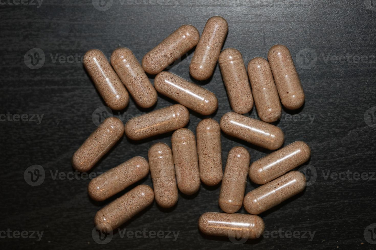 Cápsulas transparentes llenas de vitaminas marrones en polvo cerca de fondo impresiones de gran tamaño de alta calidad foto