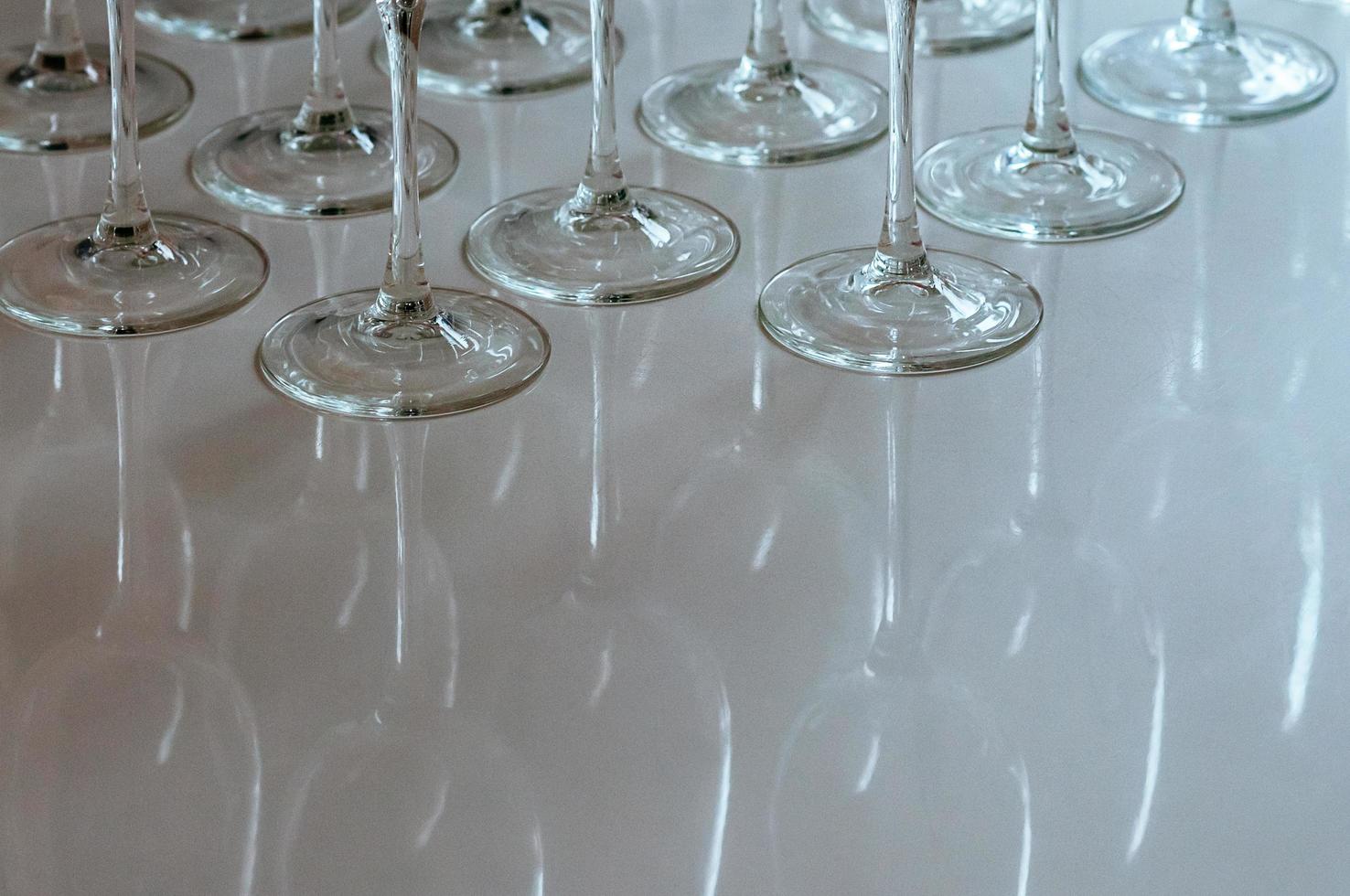 Vasos vacíos de tallo alto en la mesa con reflejos foto