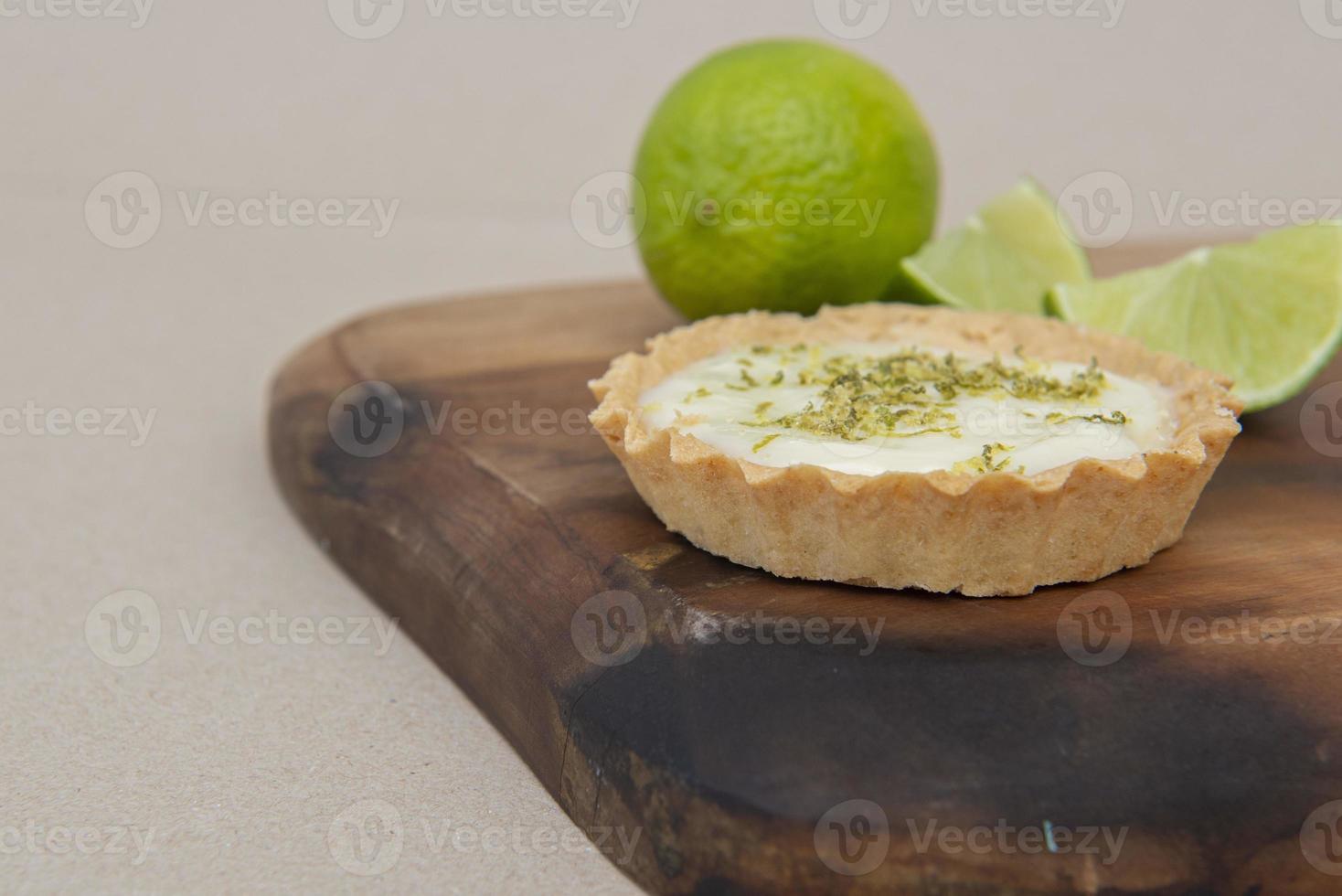 Close up of lemon pie on the table with citrus fruits. Traditional french sweet pastry tart. Delicious, appetizing, homemade dessert with lemon curd cream. Copy space photo