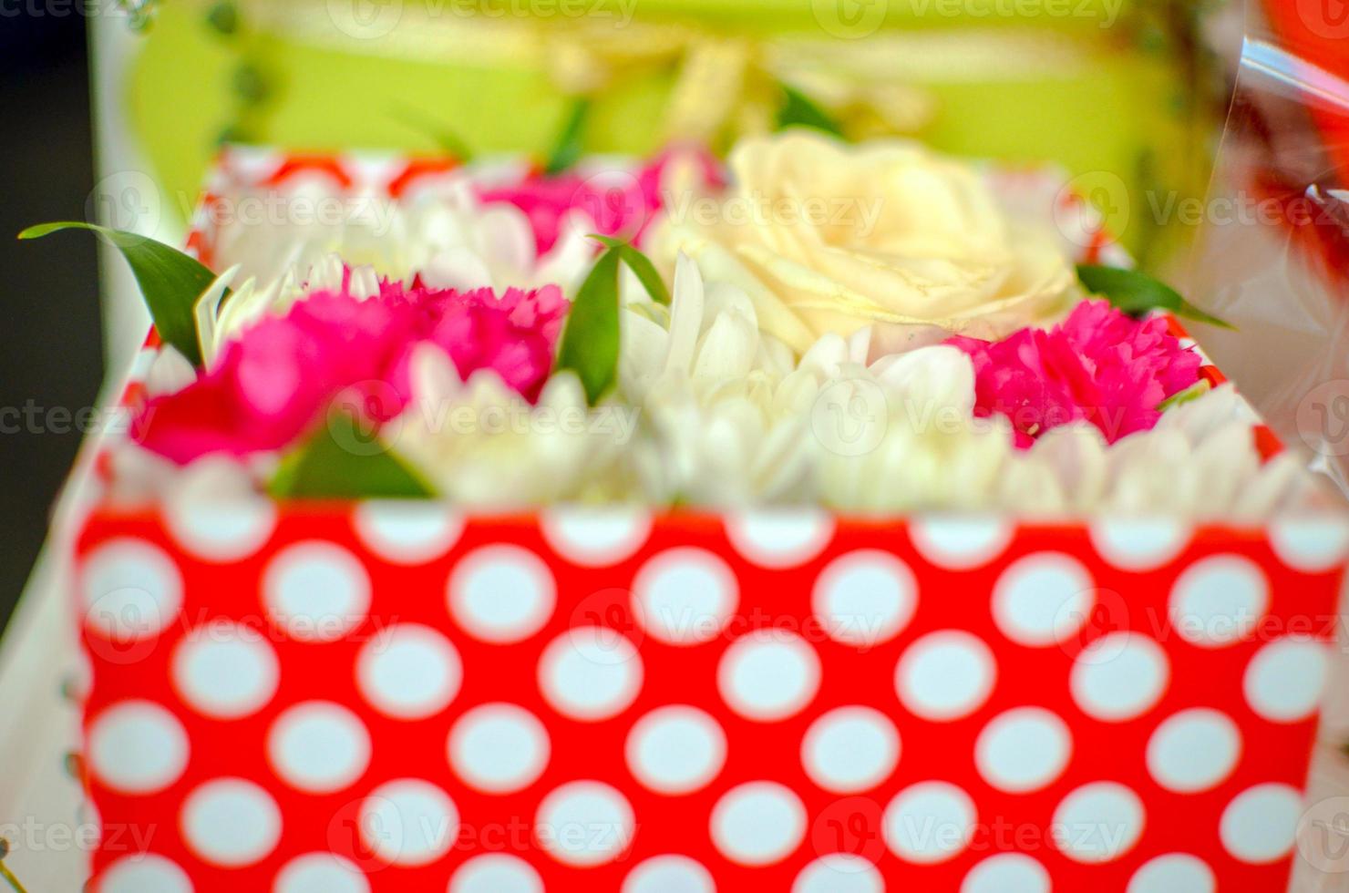 Beautiful bouquet of mixed flowers of chrysanthemums, cloves and roses in red box photo
