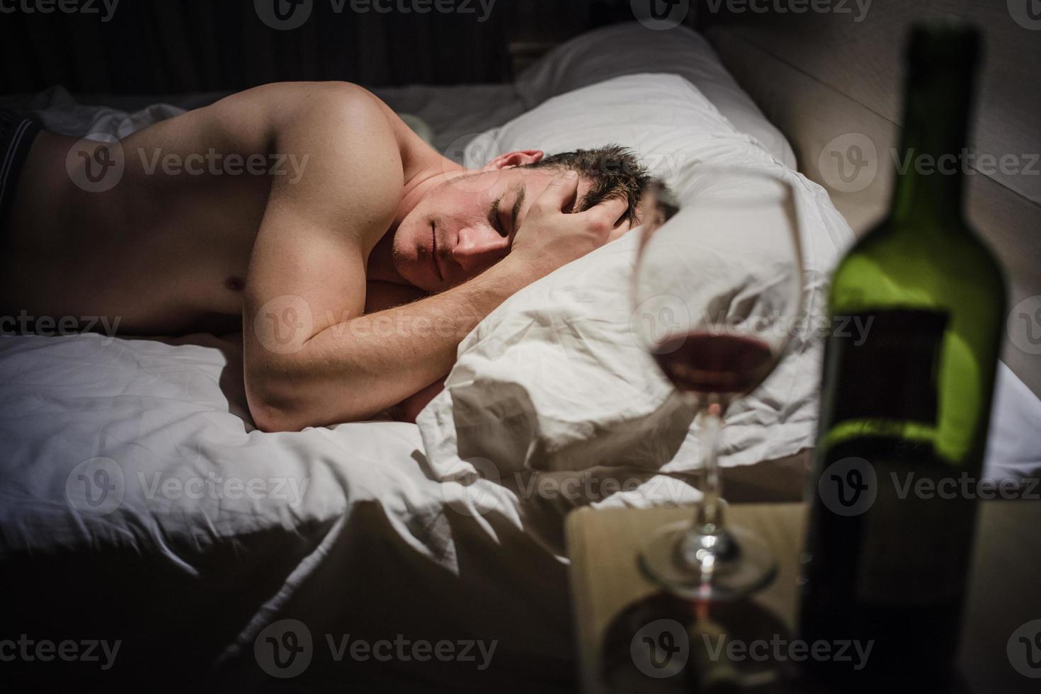 Hombre resaca con dolores de cabeza en una cama por la noche foto
